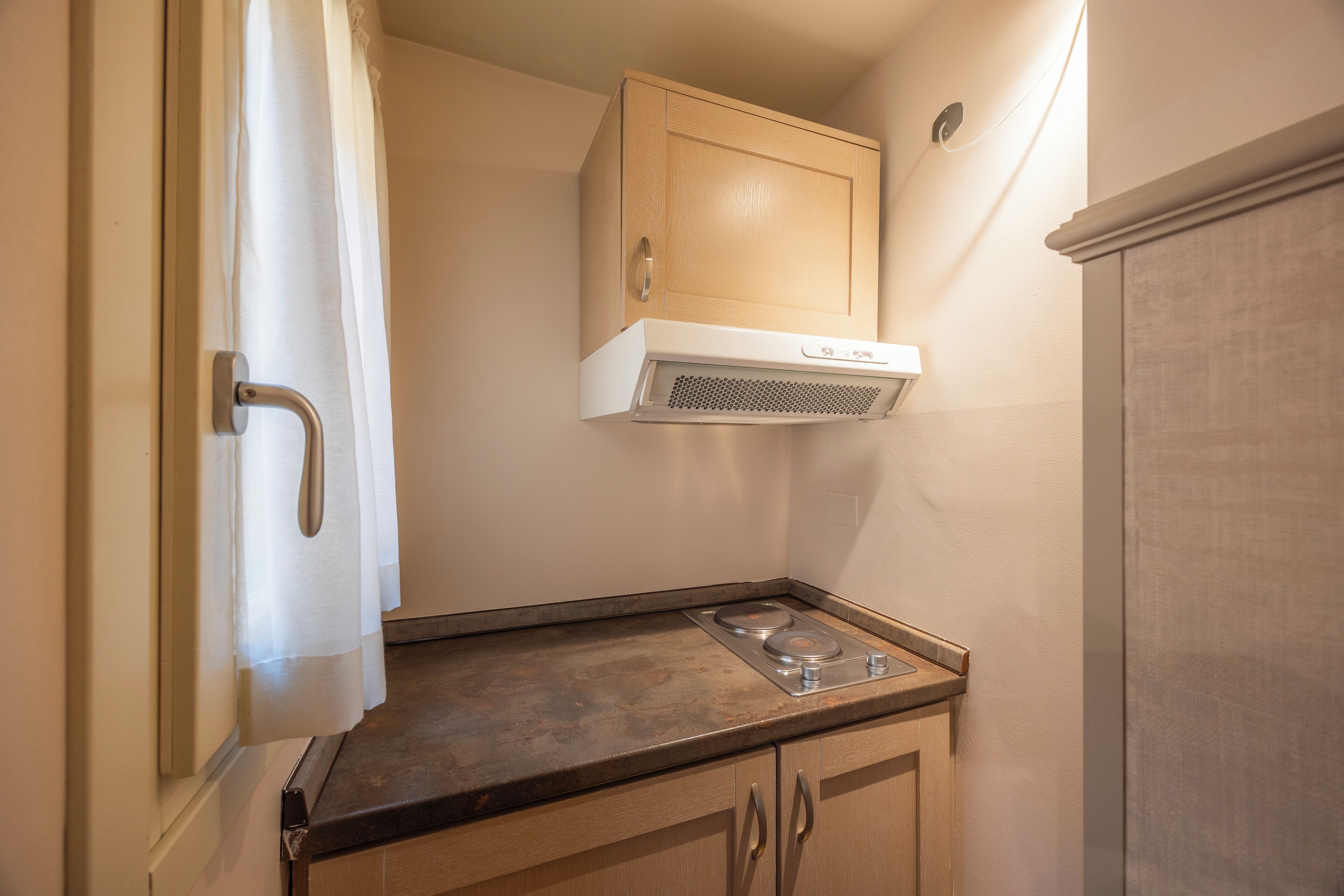 A kitchen with a stove, wooden cabinets, and a white range hood.