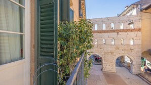 A stone bridge with arches, a balcony with a metal railing, and a building with a window and shutters. - Residenza Palazzo Negri (Verona)
