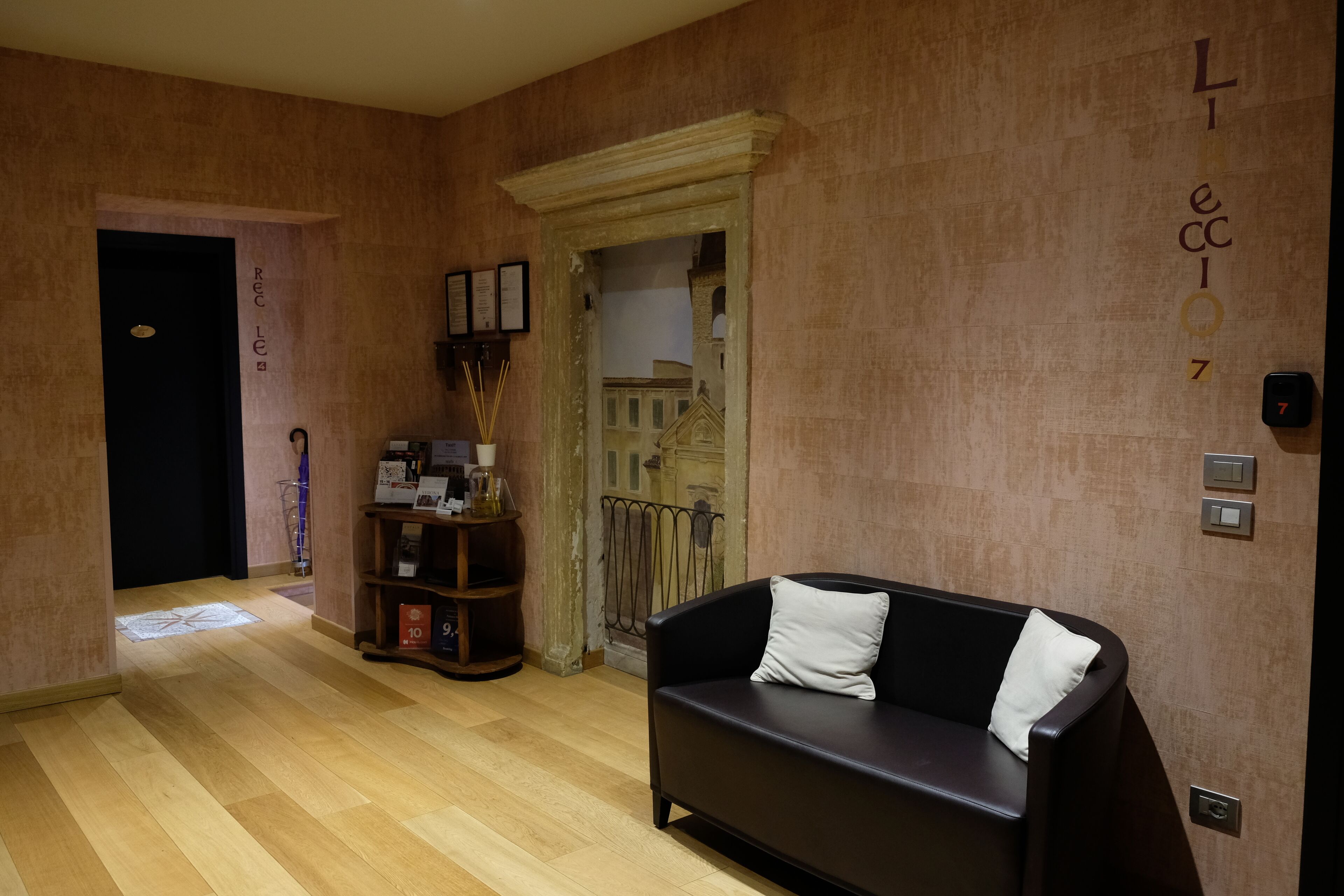 Un salon moderne avec un canapé noir, une bibliothèque en bois et un miroir décoratif.