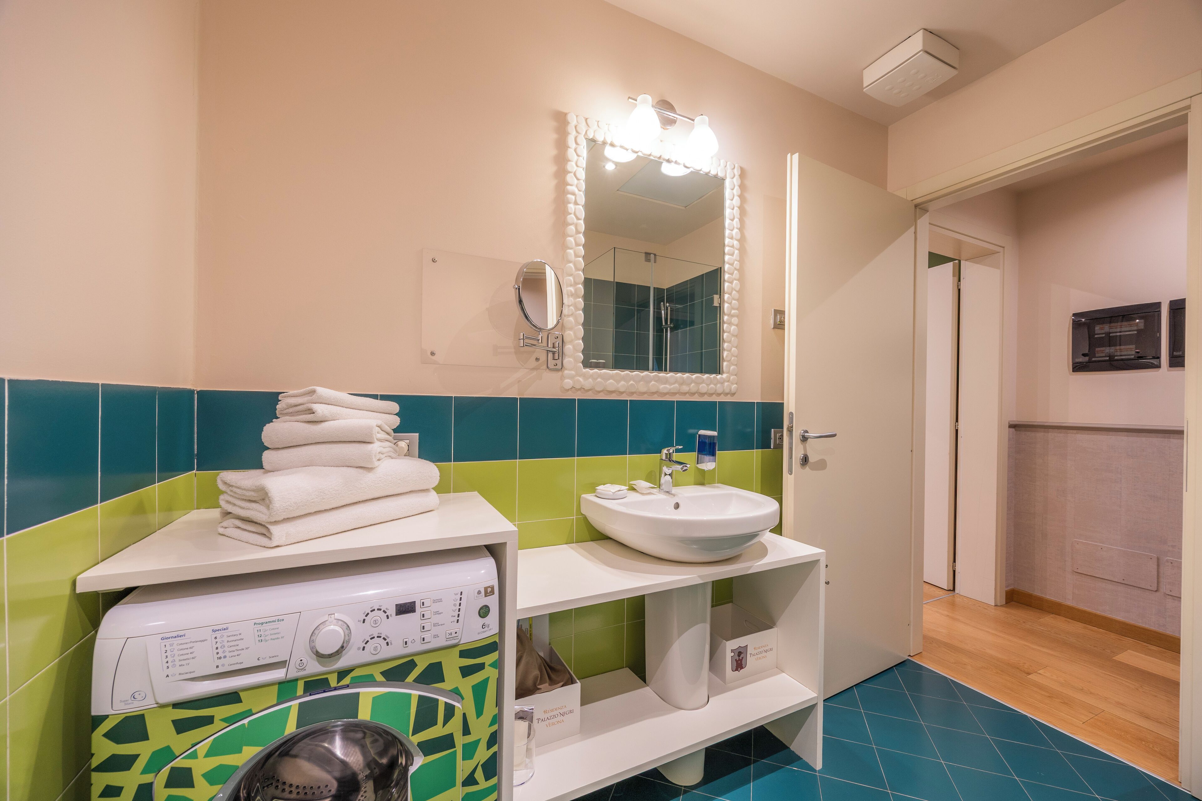 Un baño con lavadora, lavamanos y espejo.