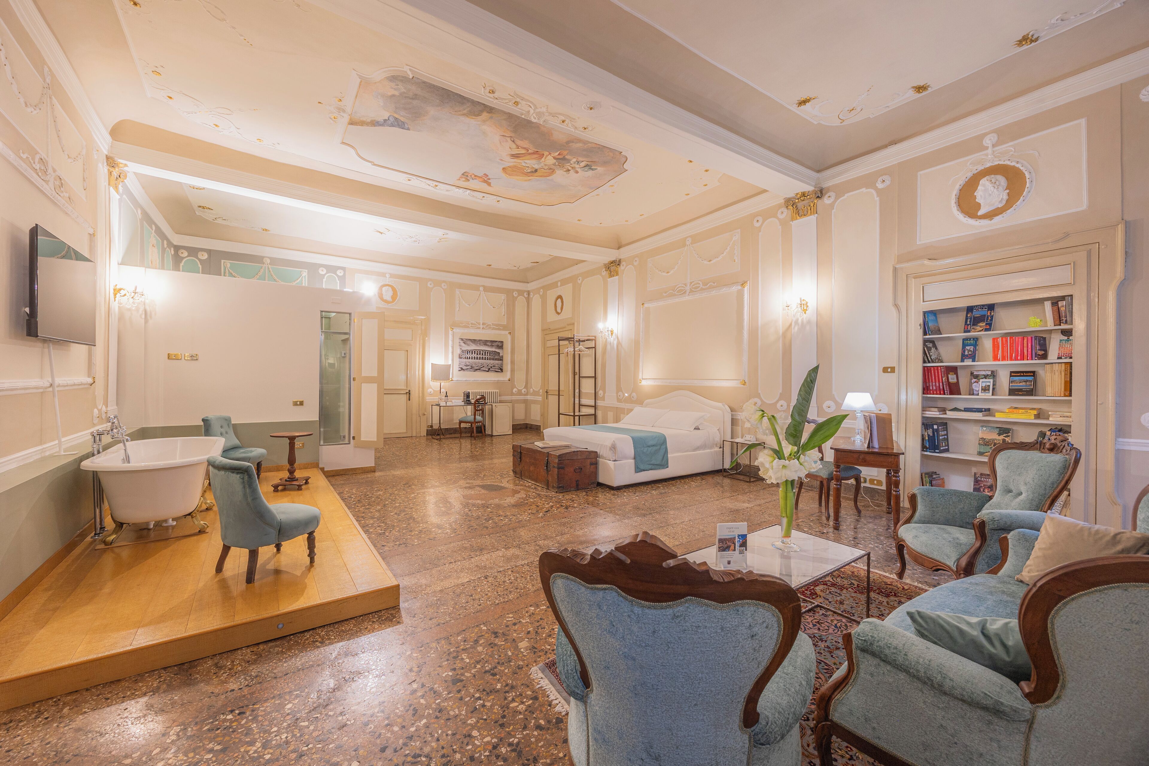 A spacious living room with a large sofa, armchairs, a coffee table, and a bookshelf.