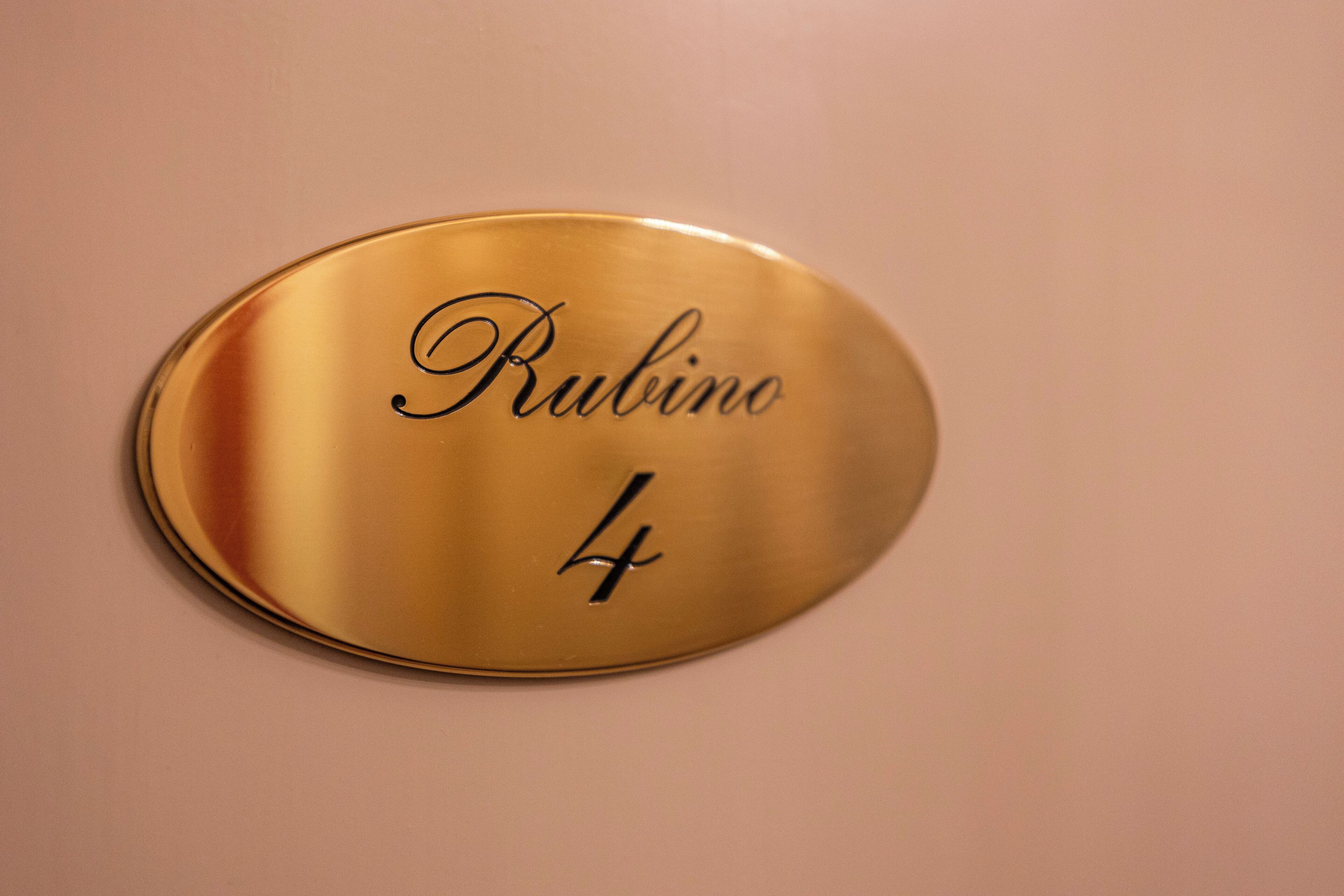 A gold-colored plaque with the name "Rubino" and the number "4" on a wall.