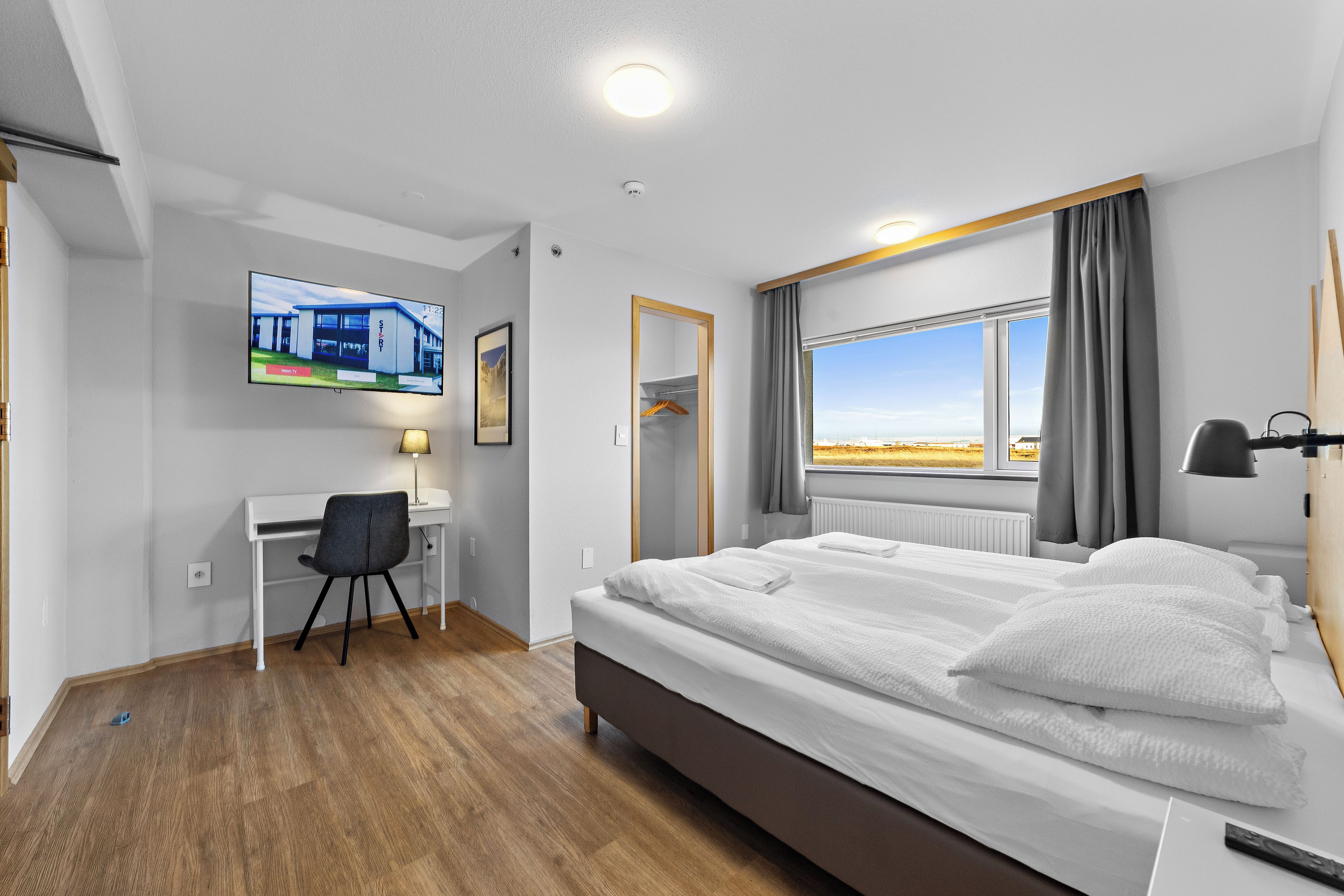 Ein Hotelzimmer mit Bett, Schreibtisch, Stuhl, Fernseher und einem Fenster mit Blick.