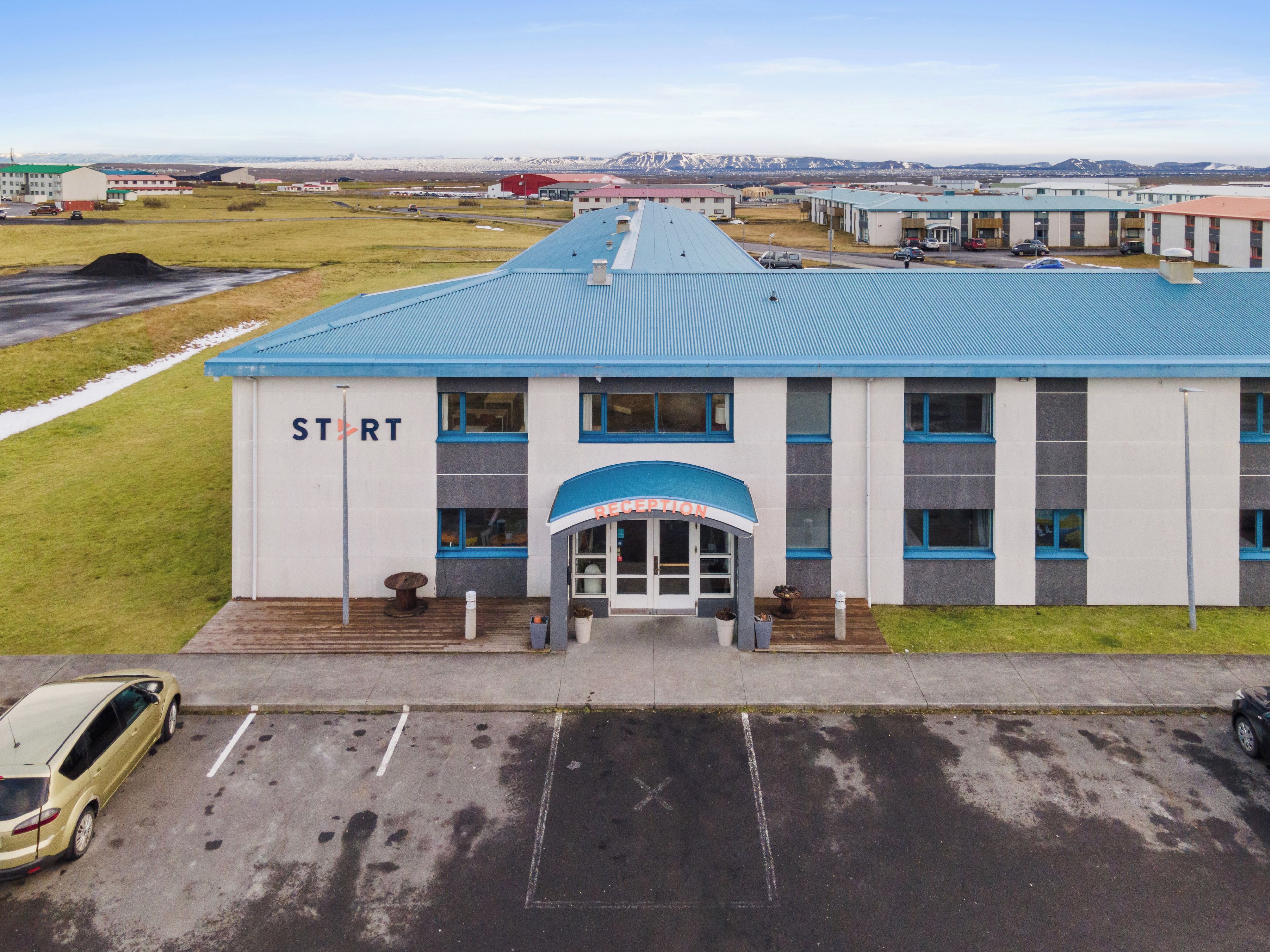 A building with a reception area, marked parking spaces, and a view of distant mountains.