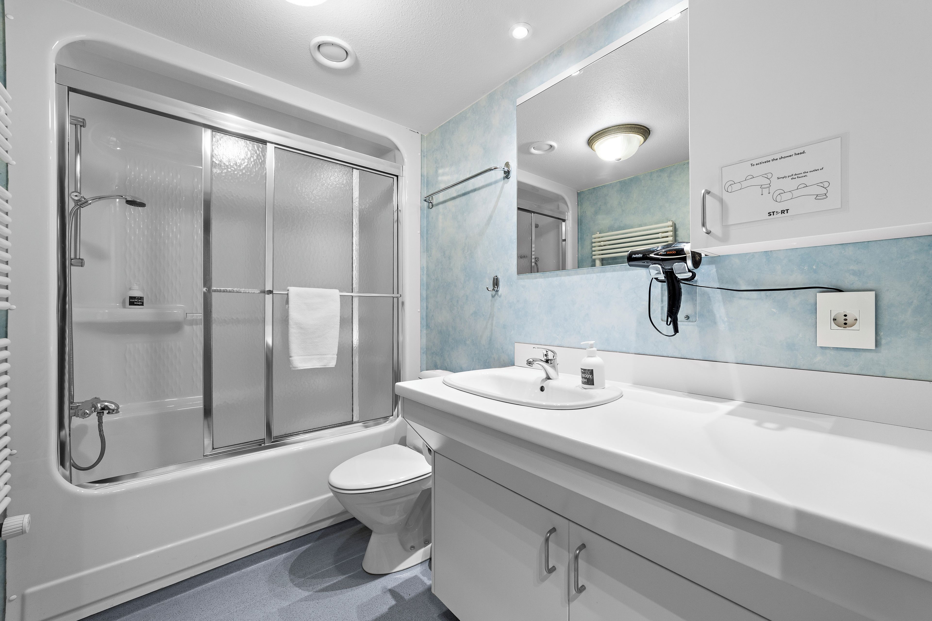 A modern bathroom with a glass-enclosed shower, a white toilet, and a vanity with a mirror.