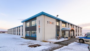 A modern building with the sign "START" on the facade, featuring a flat roof and large windows. - Start Hostel (Reykjanesbær)