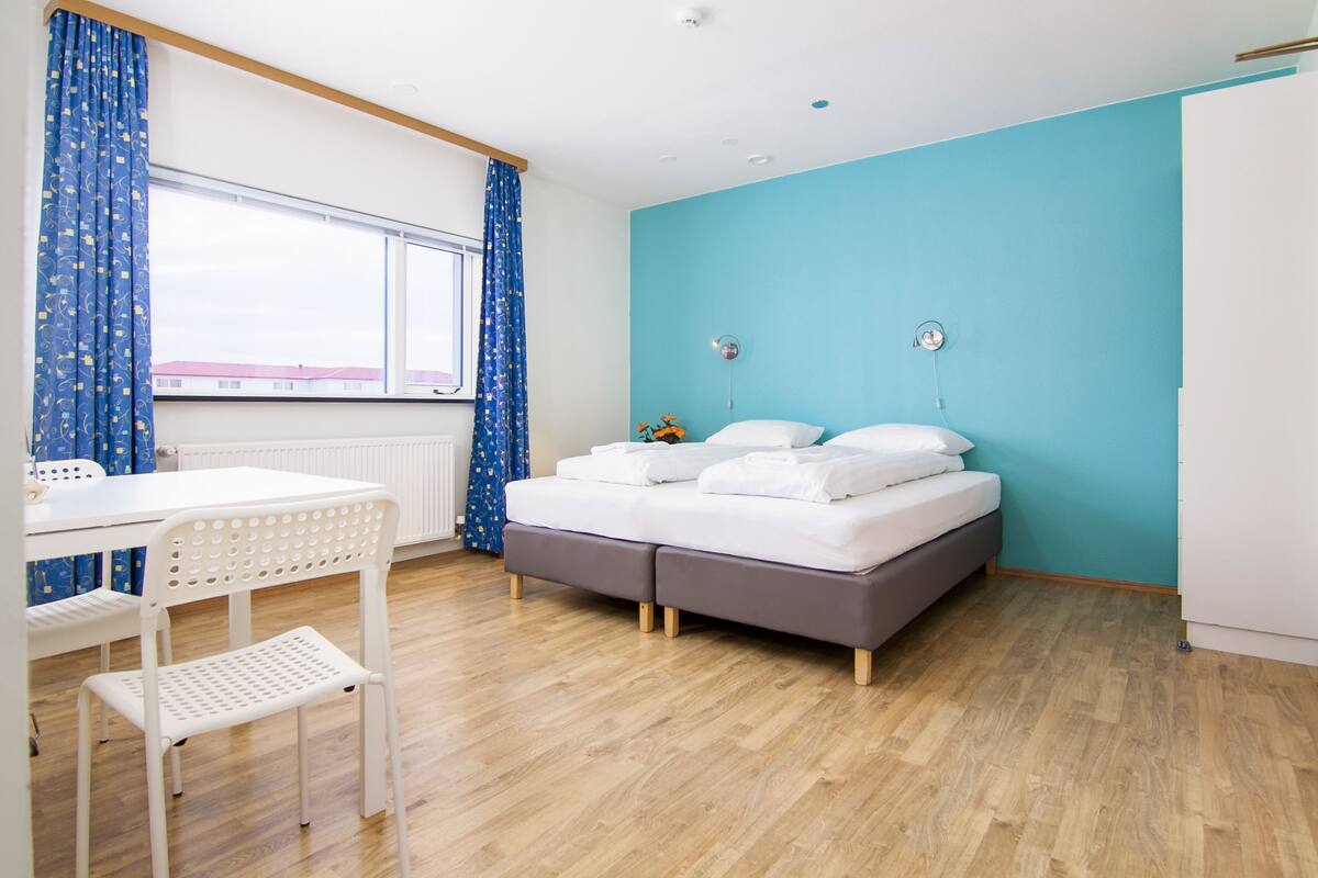A bedroom with a bed, a desk, and a chair.