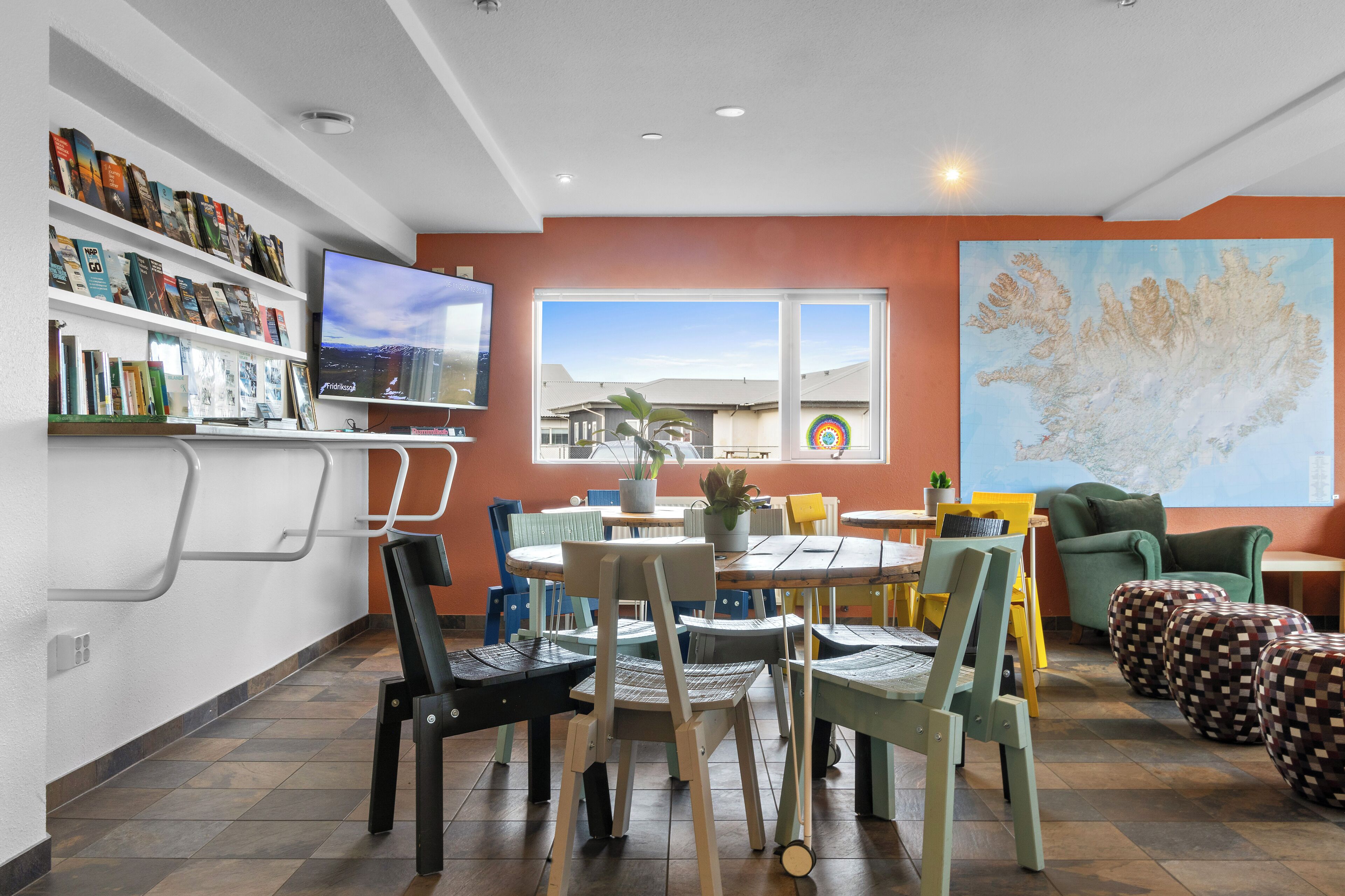 Una sala de estar moderna con comedor, televisor montado en la pared y un amplio ventanal con vistas al exterior.