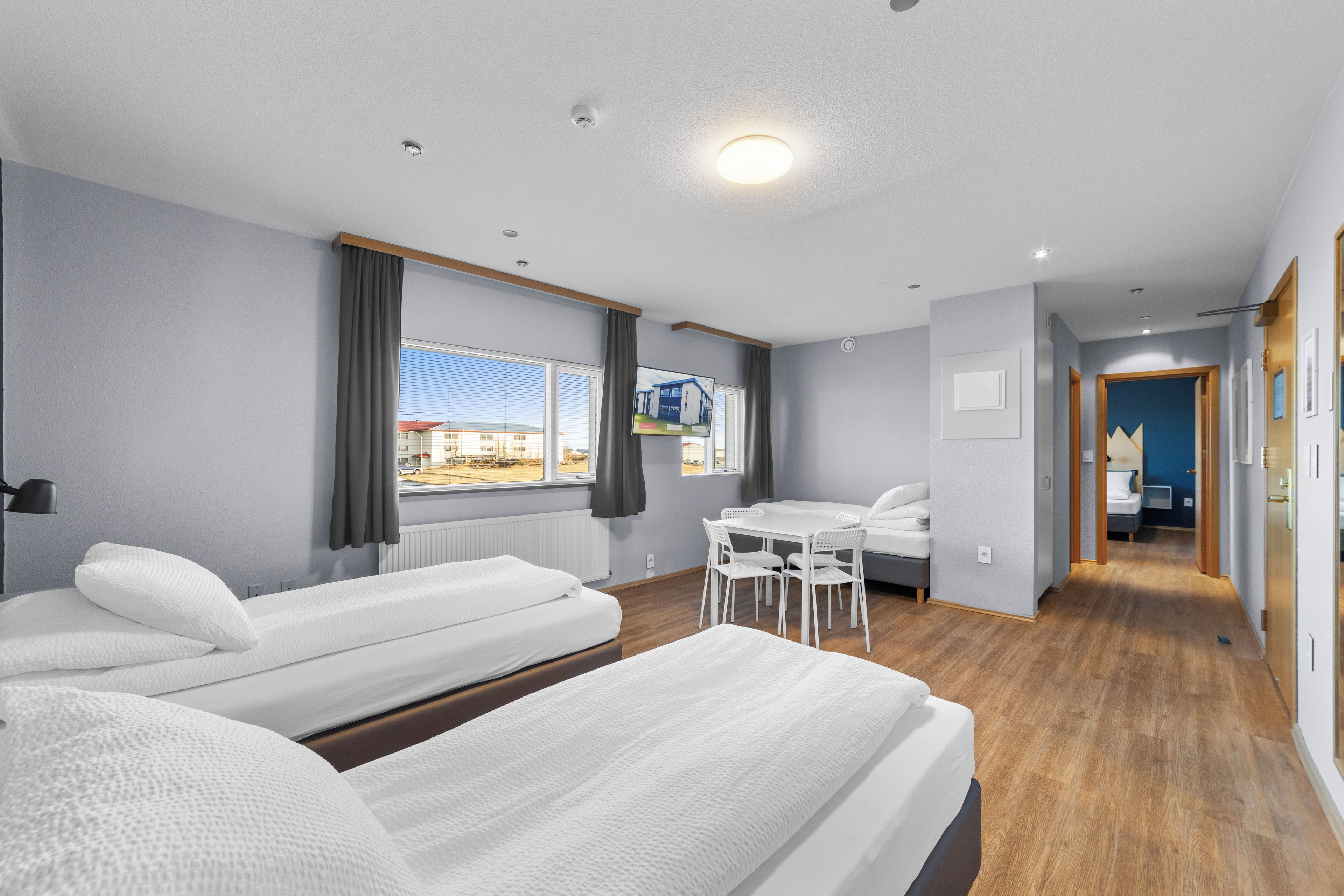 Ein Hotelzimmer mit zwei Betten, einem Esstisch und Blick ins Freie.