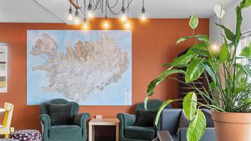 A modern living room with a large map on the wall, comfortable seating, and a large green plant.