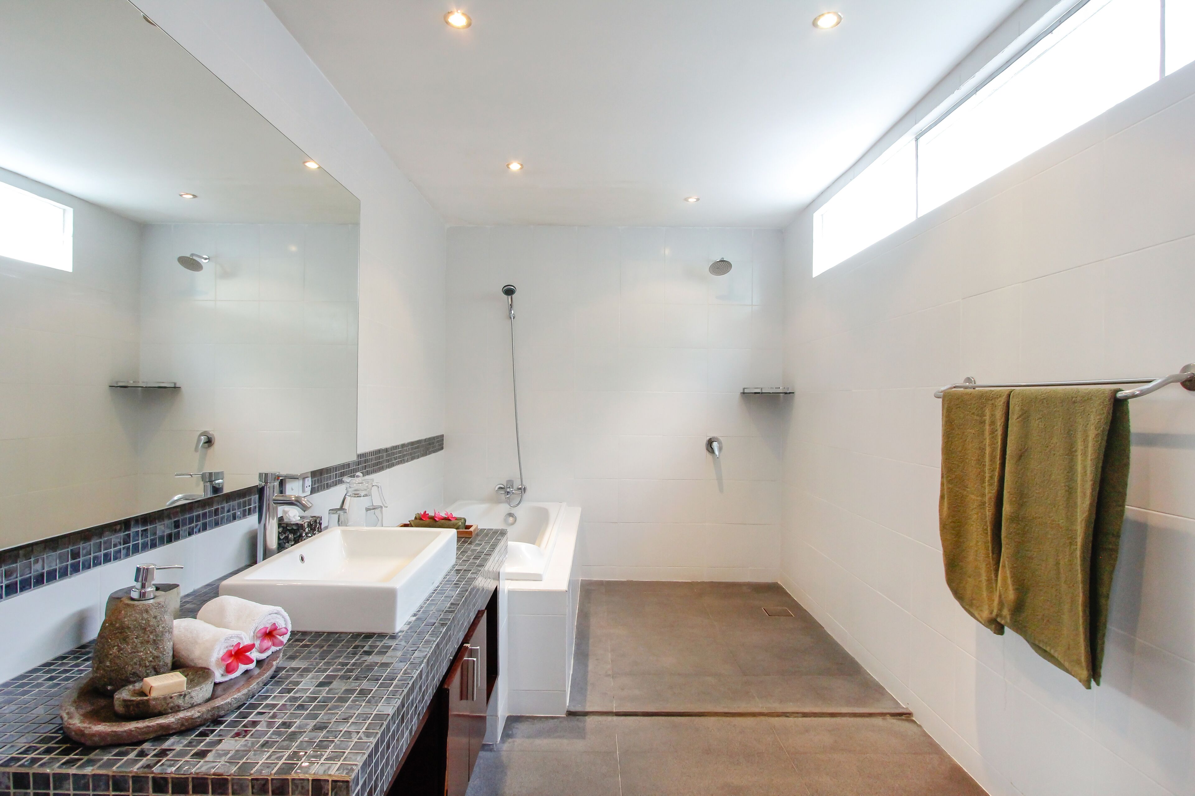 A modern bathroom with a large mirror, a bathtub, and a shower.