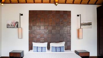 A bedroom with a large bed, wooden headboard, two bedside tables, and wall-mounted lamps.