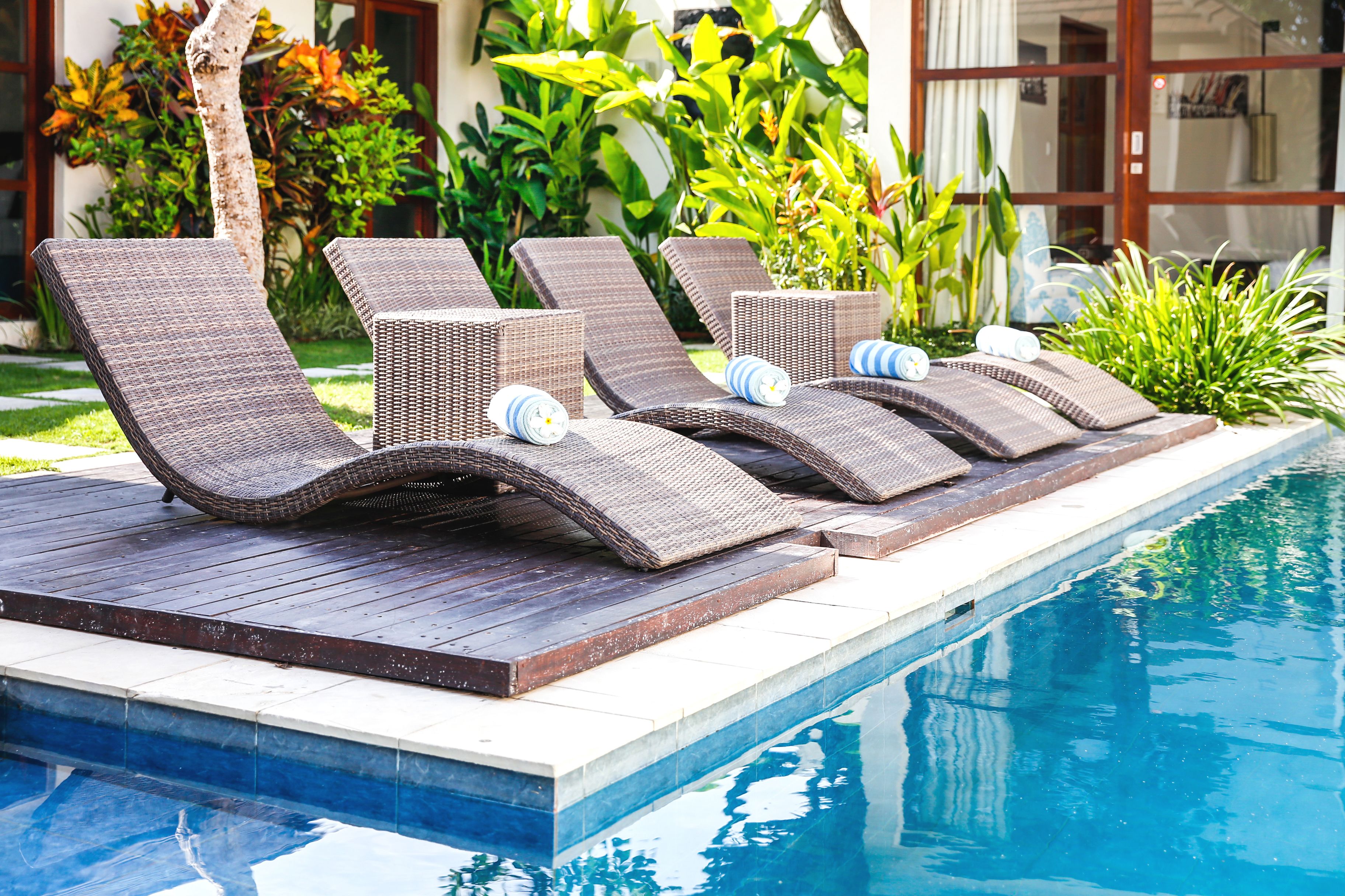 A poolside area with lounge chairs and a wooden deck.