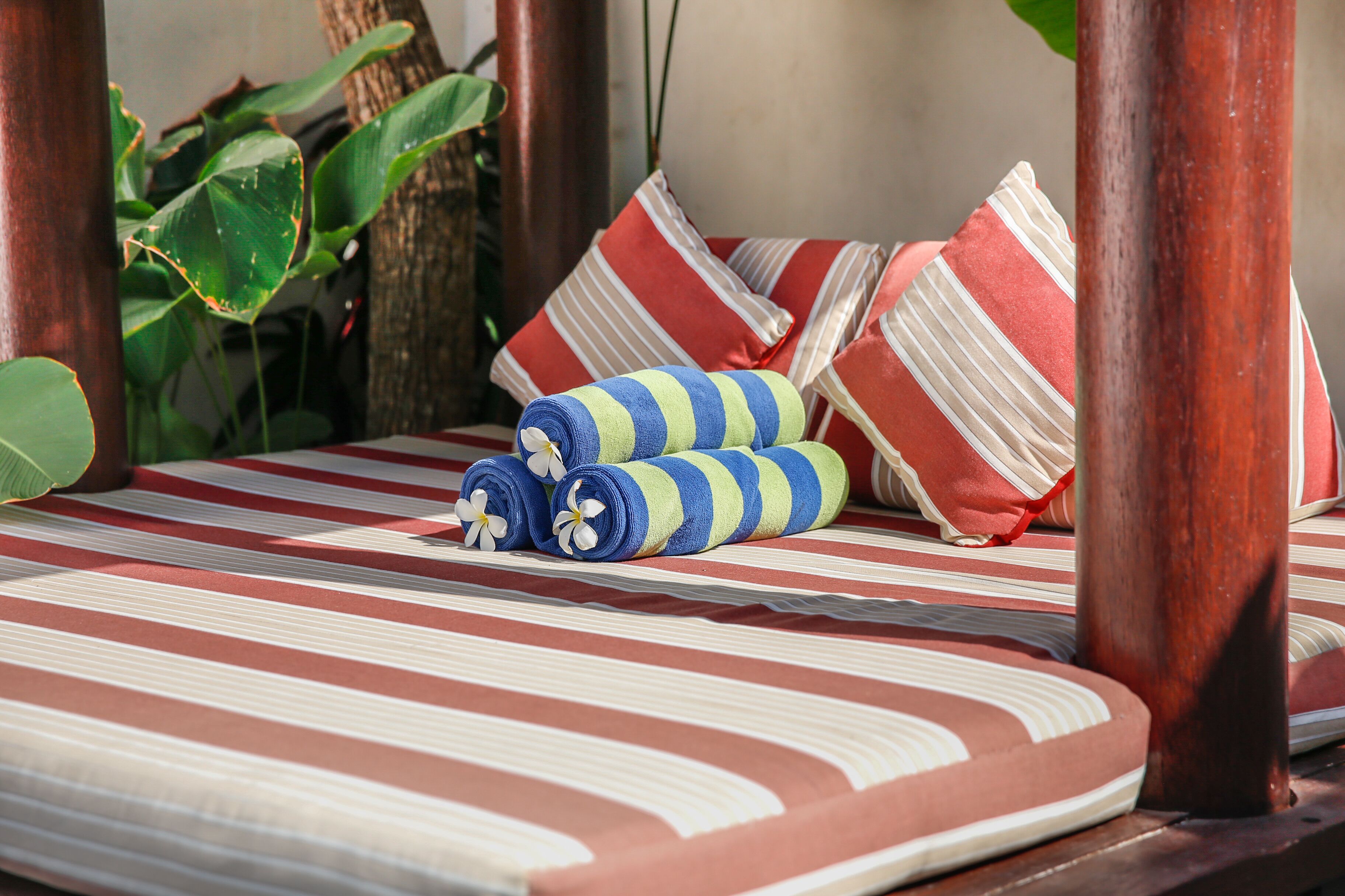 A bed with striped bedding, rolled towels, and striped pillows.