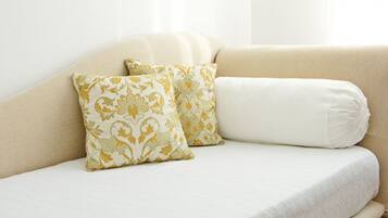Ein beiges Sofa mit zwei gemusterten Kissen und einem schlichten weißen Kissen.