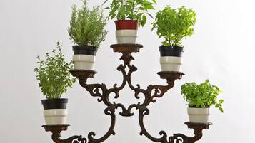 Un soporte metálico decorativo con múltiples macetas que contienen diversas plantas verdes.