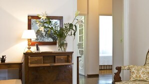A room with a wooden dresser, a chair, a lamp, and a painting on the wall. - B&B Albaro (Genoa)
