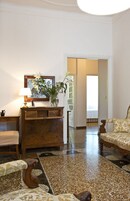 A room with a wooden dresser, a chair, a lamp, and a painting on the wall.