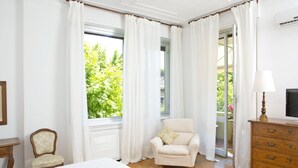 A bedroom with a bed, a chair, a dresser, and a window with curtains. - B&B Albaro (Genoa)