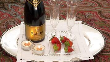 A bottle of Ruinart champagne, two glasses, strawberries, and candles on a tray.