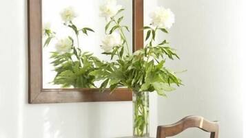 Una scrivania in legno con una sedia, un vaso con fiori bianchi e un quadro incorniciato appeso al muro.