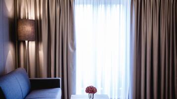 A modern living room with a sofa, a table with a vase, and curtains.