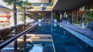 A modern outdoor pool area with lounge chairs, potted plants, and a large reflective disco ball. - Hotel Gerl (Wals-Siezenheim)
