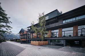 A modern hotel with a multi-story structure, outdoor seating area, and a view of mountains in the background. - Hotel Gerl (Wals-Siezenheim)