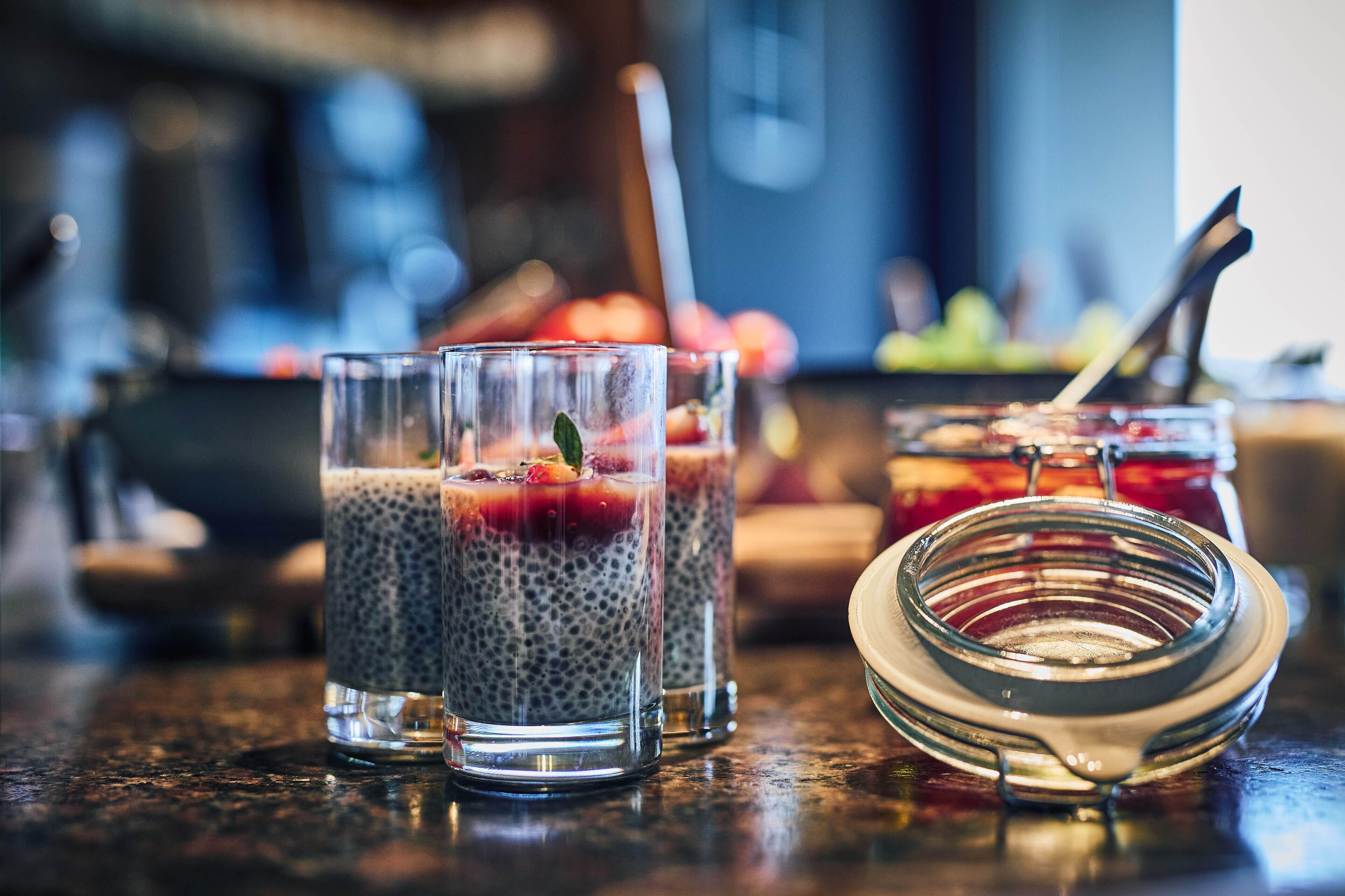 Trois verres de pudding aux graines de chia, garnis de fruits, sont posés sur le comptoir d’un bar.