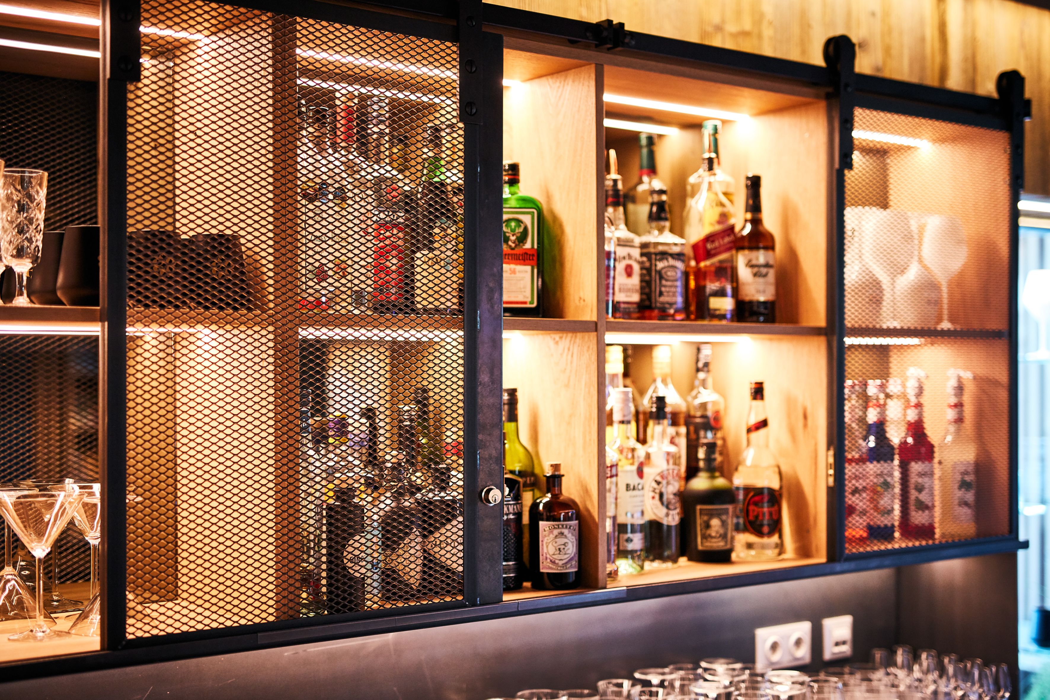 Un espace bar avec des étagères remplies de bouteilles d’alcool et de verres.