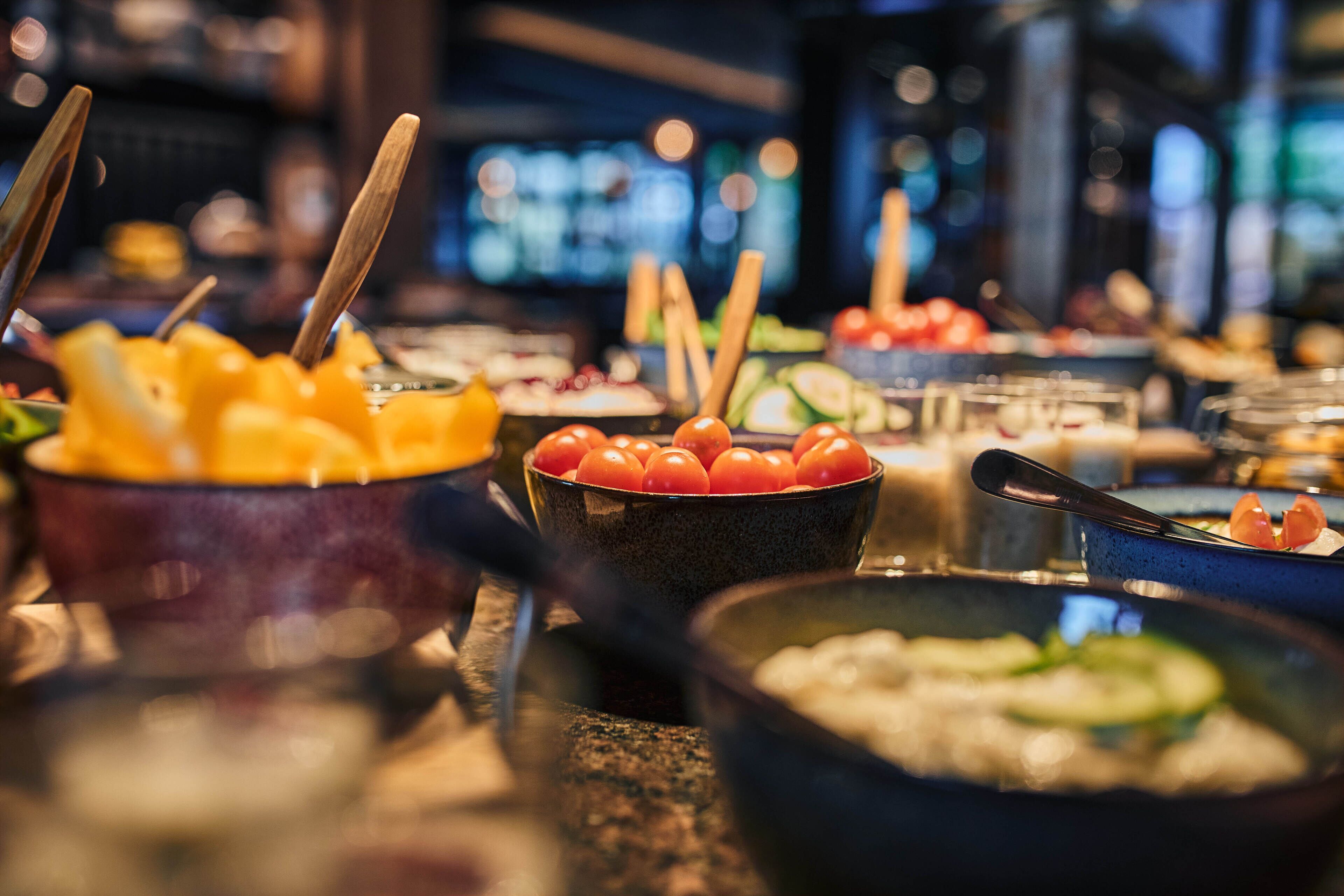 A buffet with various dishes, including fruits, vegetables, and possibly some seafood.