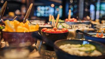 A buffet with various dishes, including fruits, vegetables, and possibly some seafood.