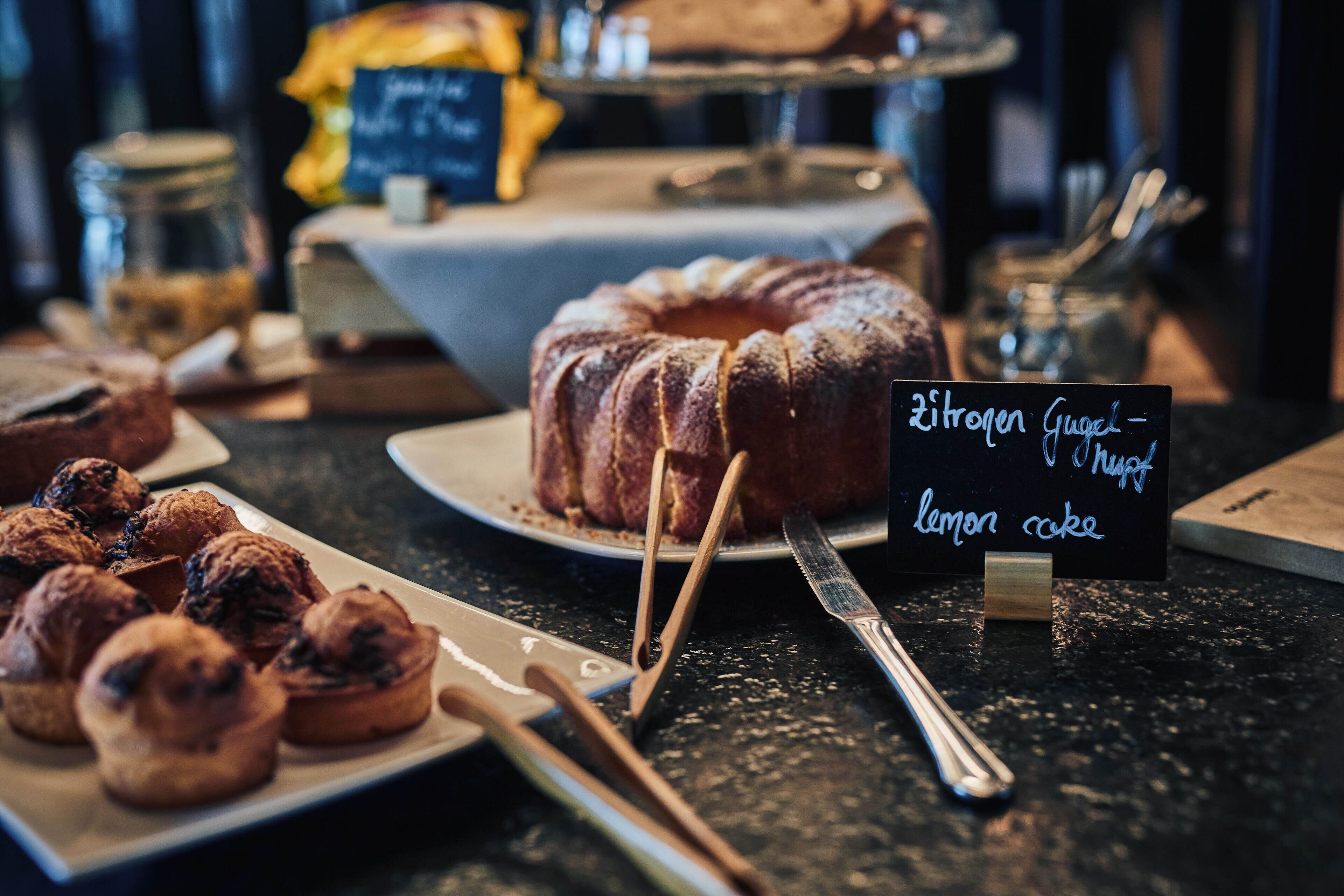 Exhibición de postres con un pastel bundt y un pastel de limón, junto a un letrero que indica los sabores.