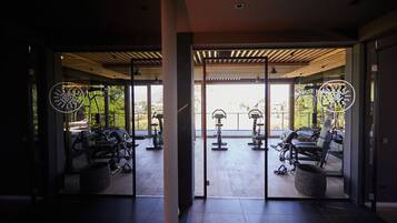 A gym with exercise equipment, large windows, and a modern interior design.