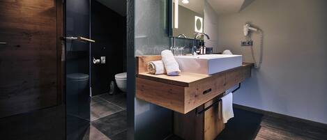 Un baño moderno con tocador de madera, cabina de ducha de vidrio y inodoro a la vista.