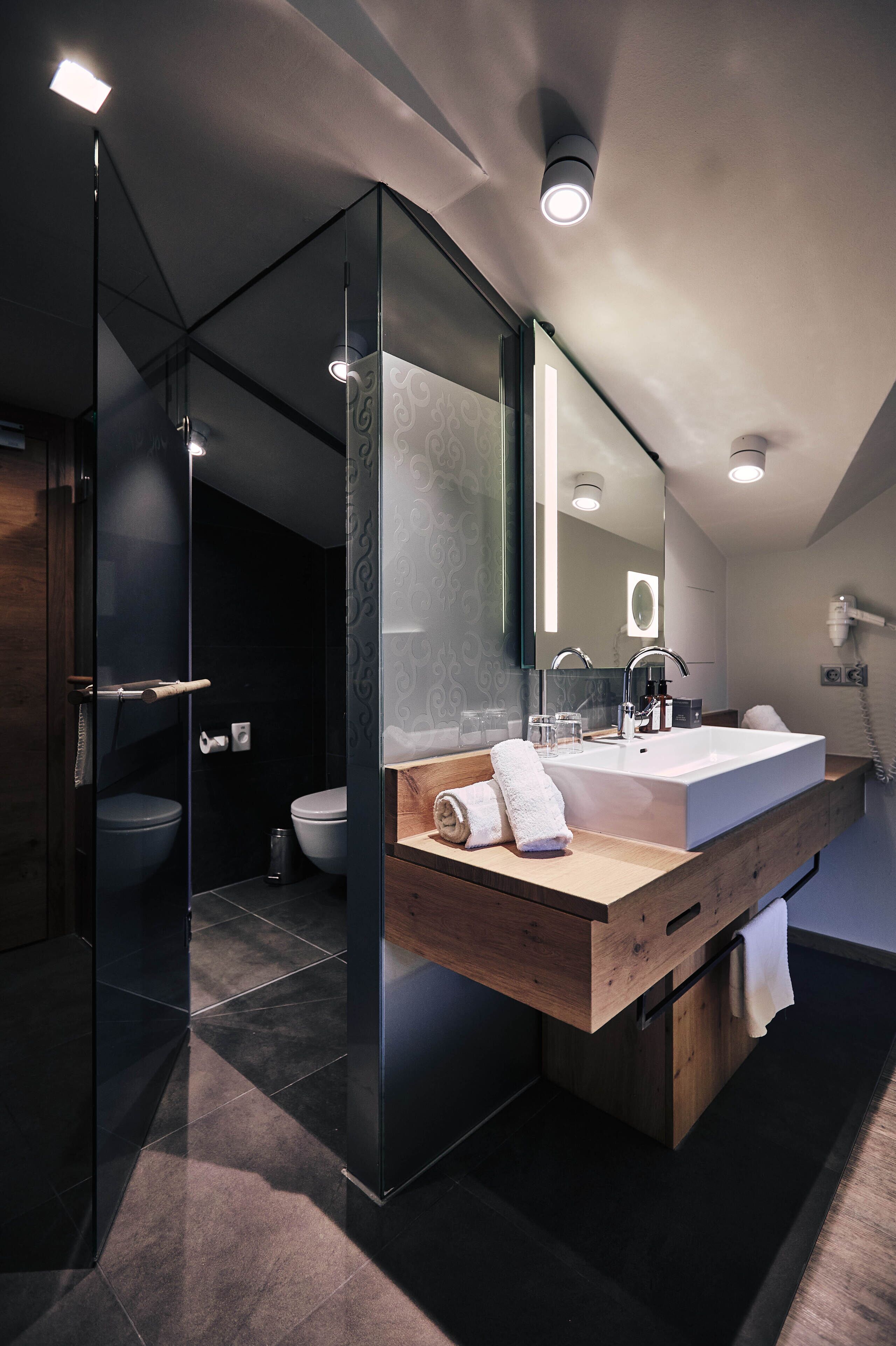 Ein modernes Badezimmer mit einer gläsernen Dusche, einem Holzlagerfläschchen und einem großen Spiegel.