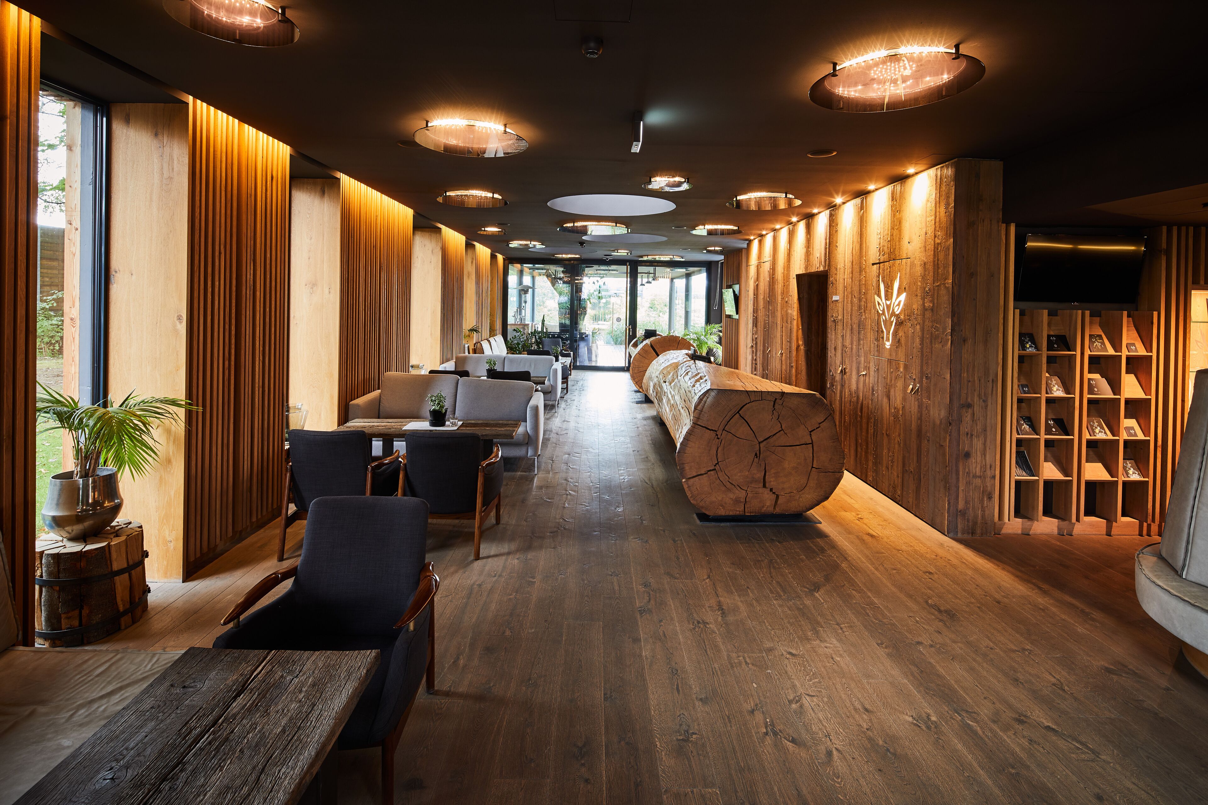 Un interior moderno con paneles de madera, un largo banco y una estantería de madera.