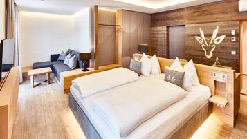 A modern hotel room with a large bed, a sofa, a desk, and a shower area.