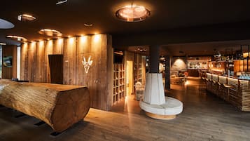 A modern interior with wooden walls, a central fireplace, and a bar area.