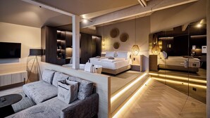 A modern hotel room with a large bed, a sofa, a TV, and a bathroom with a mirror. - Hotel Gerl (Wals-Siezenheim)