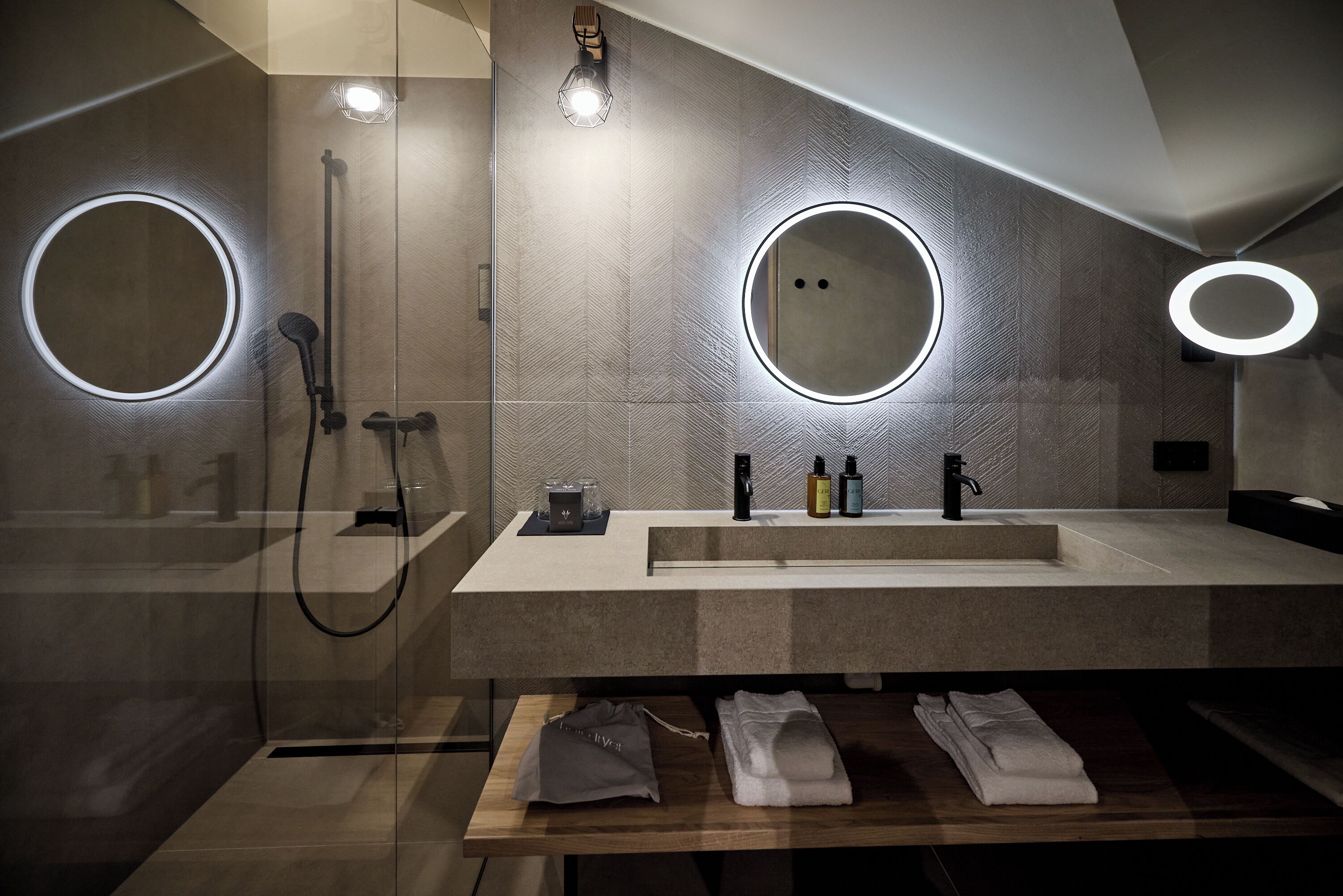 A modern bathroom with two large mirrors, a shower, and a vanity with a sink and towel rack.