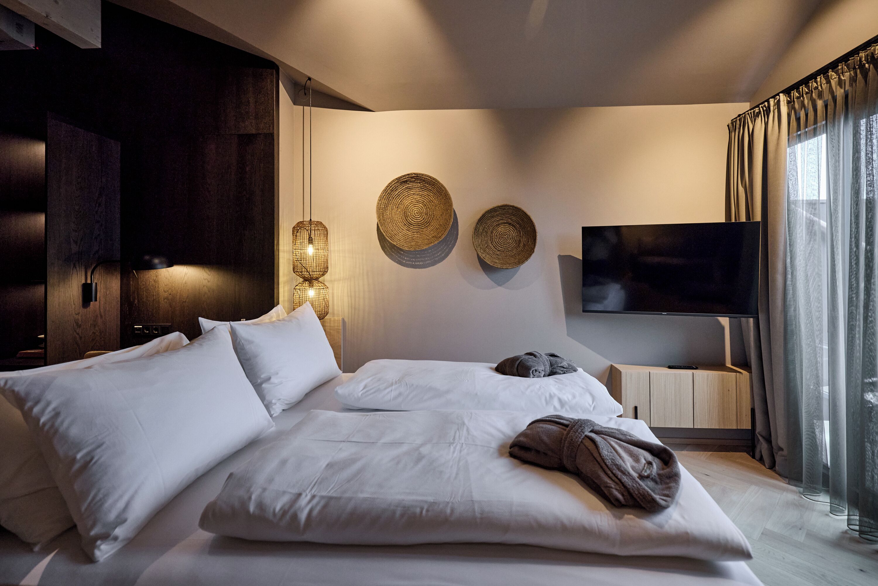 Une chambre d’hôtel avec un grand lit, une télévision et un luminaire fixé au mur.