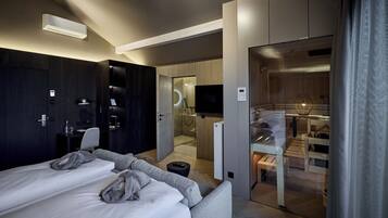Et moderne hotelværelse med seng, sofa, skrivebord og et badeværelse, der kan ses igennem en åben dør.