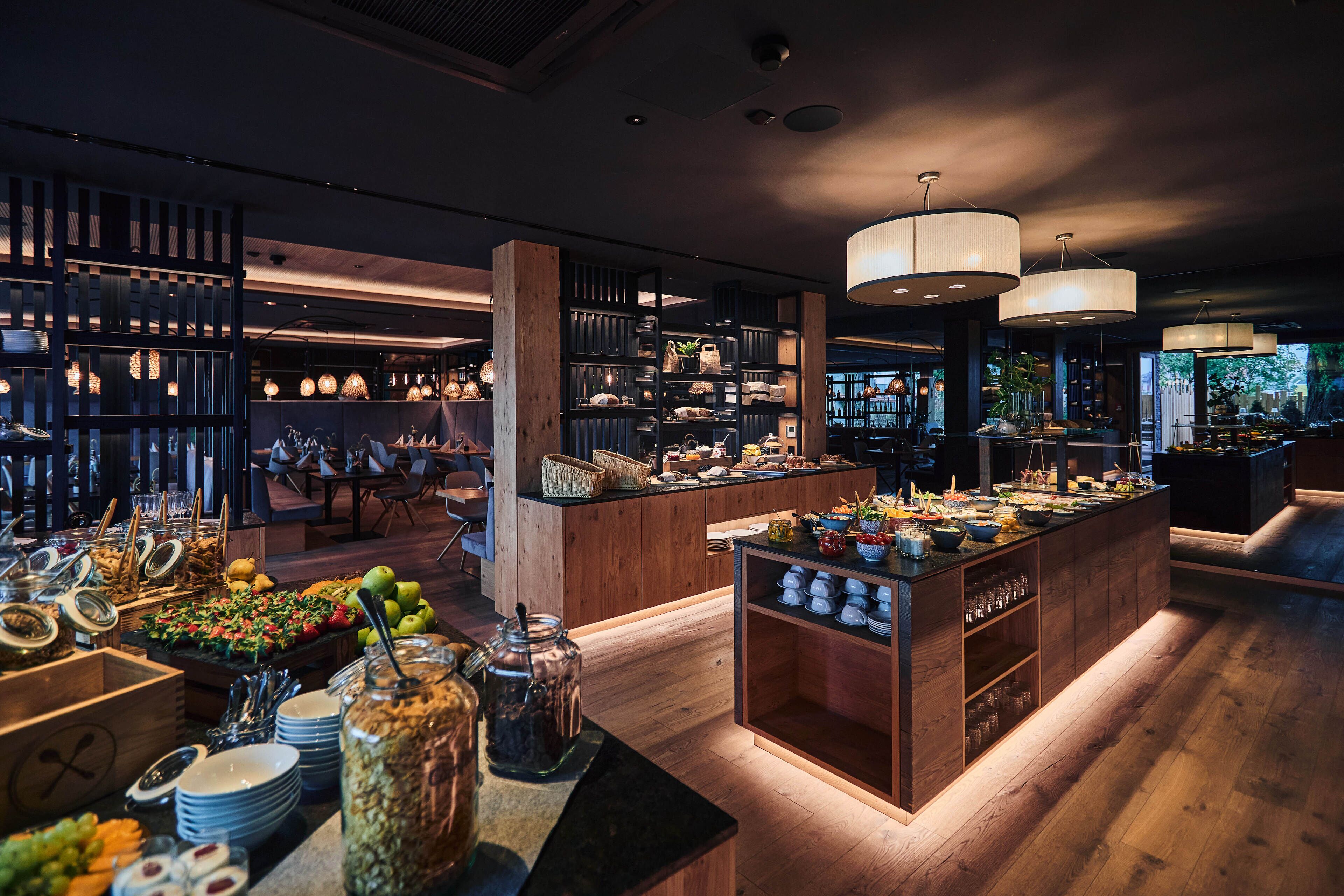 Un espace buffet proposant une variété de plats, des meubles en bois et des luminaires suspendus.