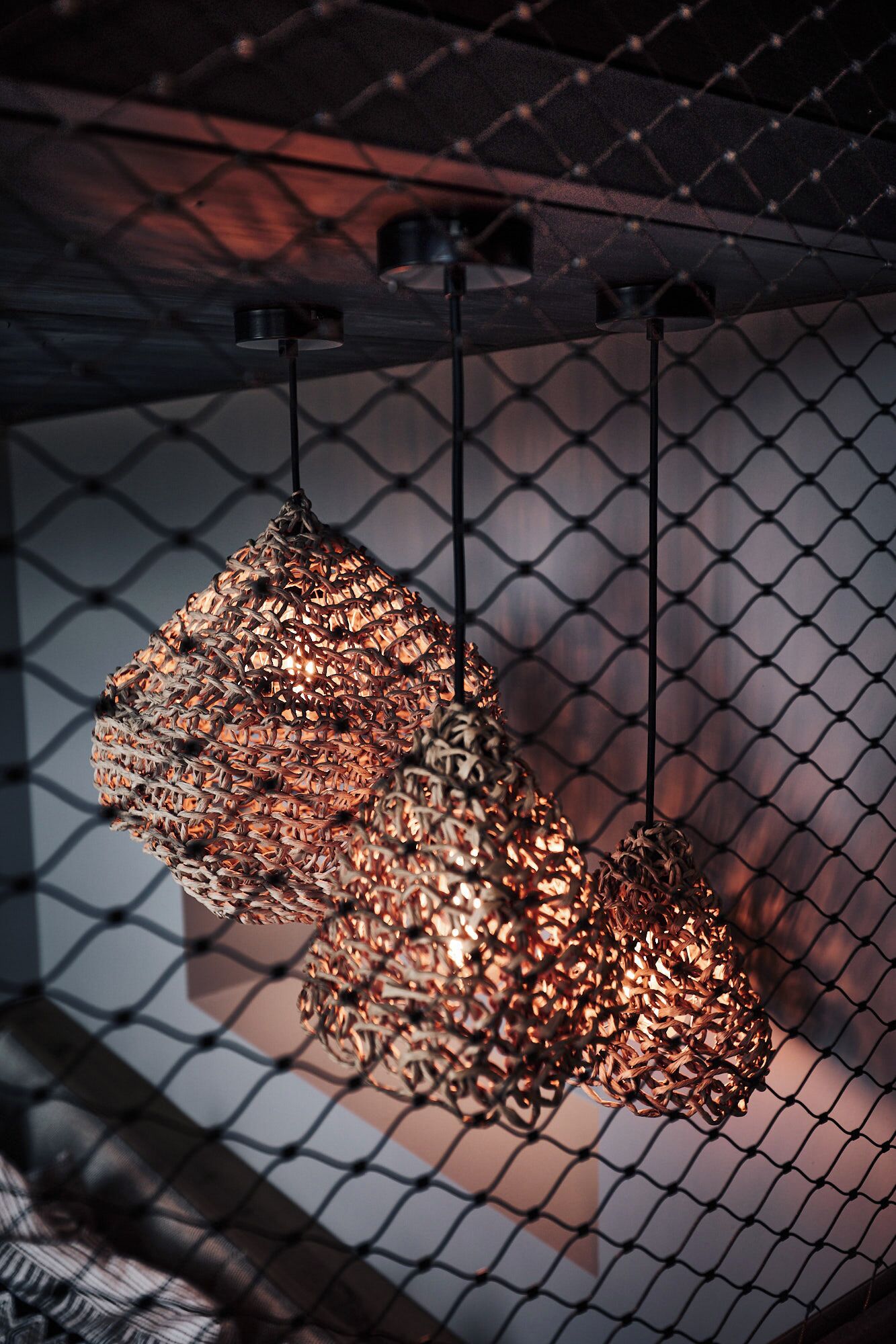 Two hanging pendant lights with a woven design, suspended from a ceiling with a chain.