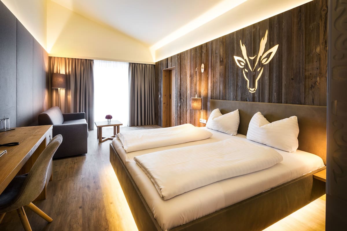 Una habitación de hotel moderna con dos camas, un escritorio, una silla y una pequeña mesa.