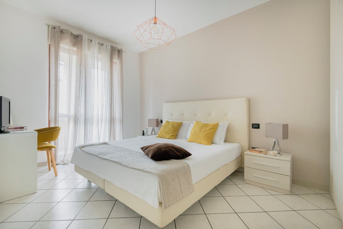 A modern bedroom with a large bed, bedside tables, a desk, and a chair.