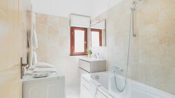 A modern bathroom with a bathtub, a shower, a vanity with a mirror, and a towel rack.