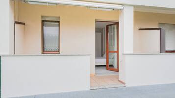 Un bâtiment moderne à la façade plate, doté d’une entrée avec une porte-fenêtre coulissante et d’un petit balcon.