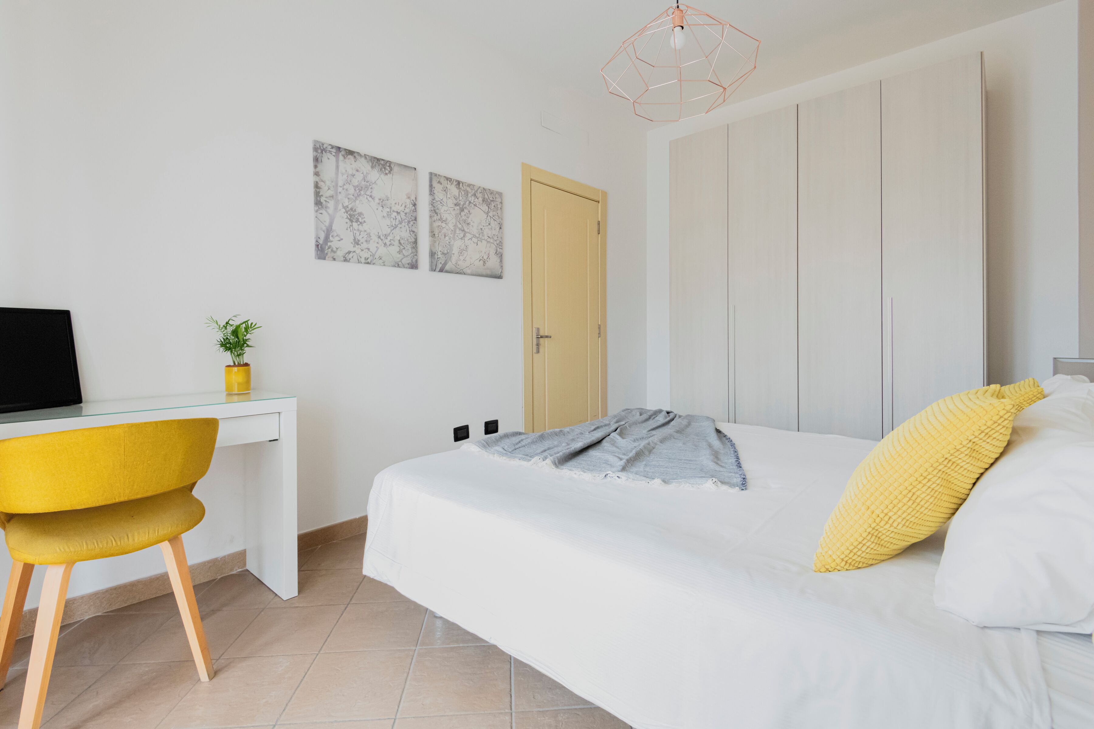 Una camera da letto con un letto, una scrivania con un computer, una sedia e una porta.